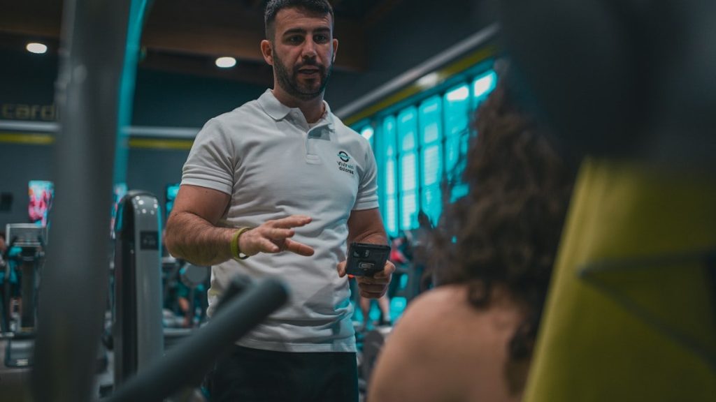 Sesión de entrenamiento en el gimnasio con un entrenador personal, enfocada en el rendimiento y el bienestar físico.